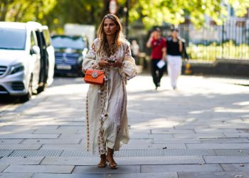 LONDON, ENGLAND - SEPTEMBER 15: A guest wears a white long dress with brown pixel geometric patterns, an orange leather bag, sandals, during London Fashion Week September 2019 on September 15, 2019 in London, England. (Photo by Edward Berthelot/Getty Images)