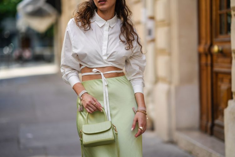 PARIS, FRANCE - JUNE 11: Ketevan Giorgadze @katie.one wears a pistachio green flowy lustrous satin midi skirt by Ottod’ame, a white cropped shirt with a crossover waist-tie by Le Ger, a mini sage green croco embossed leather bag from By far, Dior friendship bracelets in pink and cream, on June 11, 2021 in Paris, France. (Photo by Edward Berthelot/Getty Images)