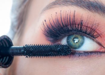 Makeup professional artist applying black mascara on lashes of model eye. Woman beauty model. Close up