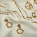 Stylish golden bijouterie on white fabric. Elegant jewelry